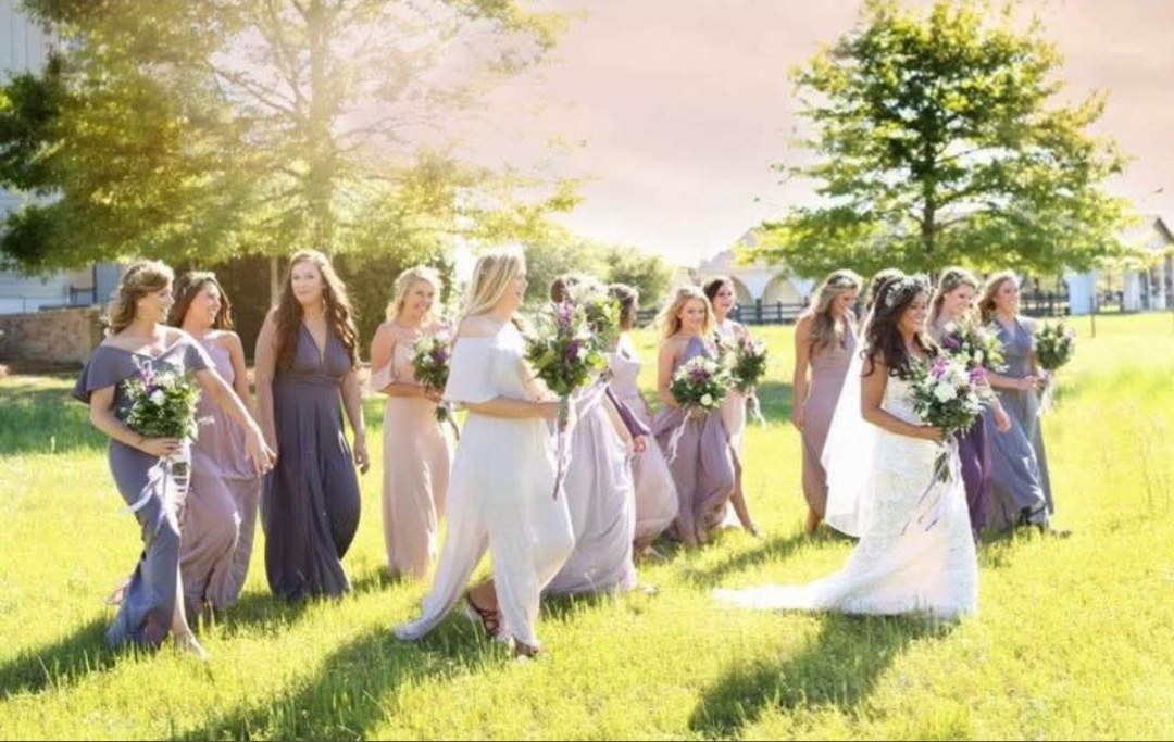 Bride and bridesmaids walking across a sunny lawn