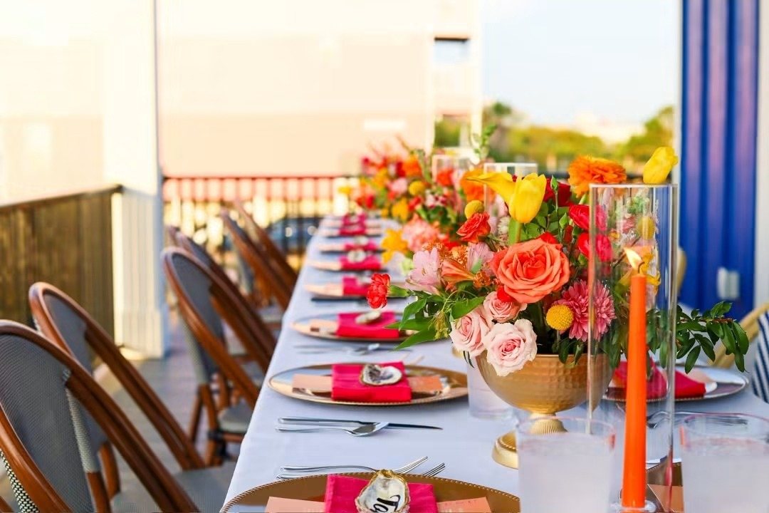 Long table with orange and pink florals and taper candles