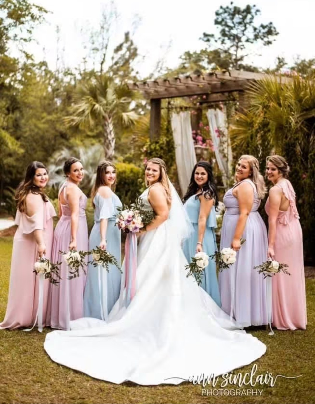 Bride with her bridesmaids in pastel dresses under a pergola