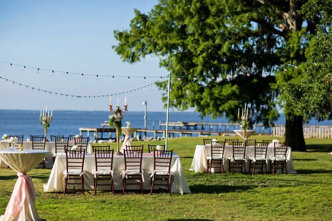 Reception tables on a lawn by the water